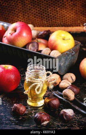 Glas Glas Honig mit Äpfel, Kastanien und Nüssen über schwarzer Holztisch mit Waben als Hintergrund. siehe Serie Stockfoto