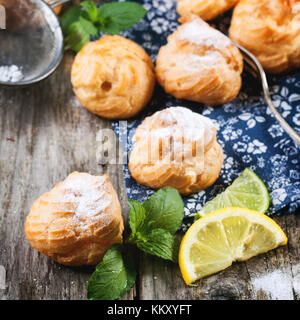 Hausgemachte Kuchen Windbeutel serviert mit Limonade auf alten Holztisch. square Bild. Stockfoto