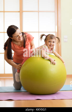 Mutter mit childdoing Übungen mit Gymnastikball zu Hause. Konzept für die Sorge um die Gesundheit des Babys. Stockfoto