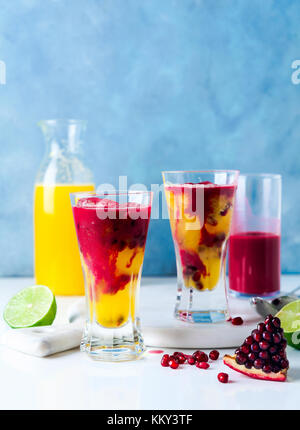 Zwei Gläser alkoholfreien Cocktail mit Orangenlikör, frisch gepresste Ananas und Granatapfelsaft und Kalk und Eis auf dem Tisch. Stockfoto