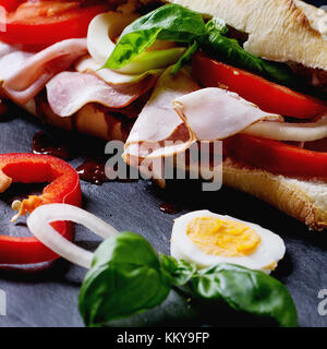 Sandwich mit Schinken, Eier, Gemüse und Ketchup über schwarzen Hintergrund. square Bild Stockfoto