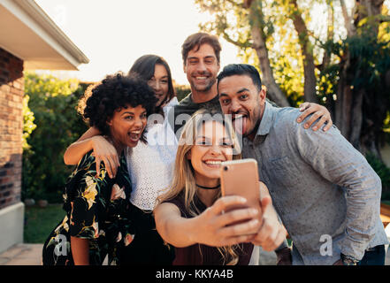 Gruppe von Menschen zusammen feiern und unter selfie. Junge Freunde bei der einweihungsparty von selfie mit Smart Phone. Stockfoto