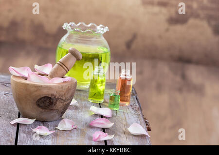 Spa und Wellness Konzept: Vorbereitung des wesentlichen Öls mit rosa Rosen, Flasche Tinktur und Mörtel auf einem Holzbrett mit allen vintage Wall Stockfoto