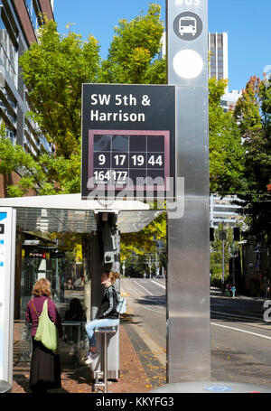 Leute an einer Bushaltestelle warten auf einen Bus, Straßenbahn oder U-Bahn in SW 5 & Harrison auf einer Straße in Portland, Oregon, USA KATHY DEWITT Stockfoto