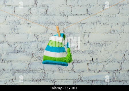 Baby Mütze und Turnschuhe trocken auf einem Seil auf einer weißen Wand. Stockfoto