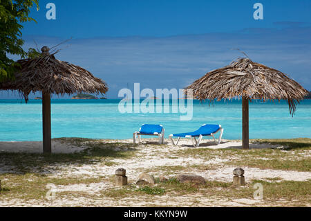 Zwei Liegestühle und Sonnenschirme an einem karibischen Strand. Stockfoto