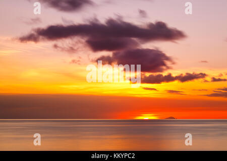 Die Insel Redonda, gehört zu Antigua und Barbuda mit einem roten Sonnenuntergang durch die Asche weg des Montserrat Volcano generiert. Stockfoto