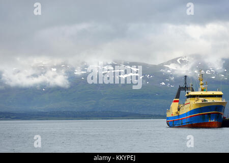 Fischereifahrzeugs auf dem Hintergrund der schneebedeckten Berge Stockfoto