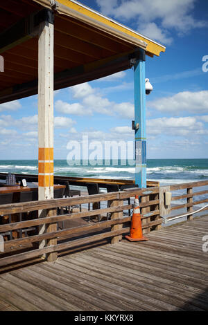 Open air Restaurant direkt am Wasser in Florida, USA, mit Blick auf ein Meer mit brechenden Wellen am Strand unter einem bewölkten Himmel Stockfoto