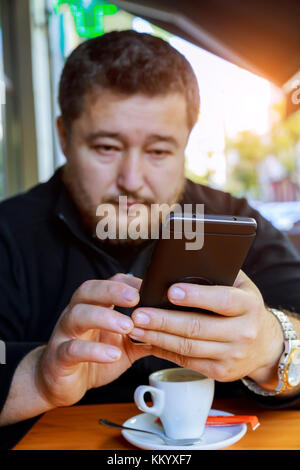 Mann mittleren Alters am Telefon sprechen ein Mann mittleren Alters, sitzt in einem Café mit einem Telefon Stockfoto