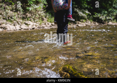 Einen kleinen Jungen und Mädchen in einen Bach an einem Sommertag. Stockfoto