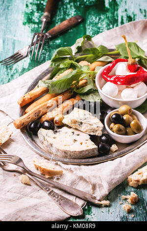 Gemischte antipasti Blau Käse, Oliven und Mozarella serviert auf silbernem Tablett über grüne Holztisch mit Vintage Gabeln. Stockfoto