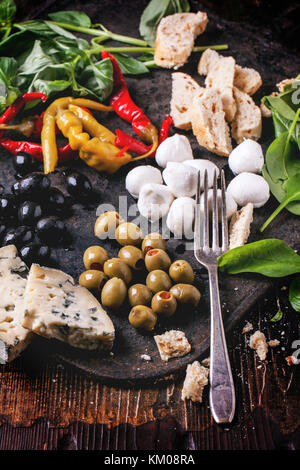 Gemischte antipasti Blau Käse, Oliven und Mozzarella serviert auf gusseisernen Brett über Holztisch mit Vintage Gabel. Stockfoto