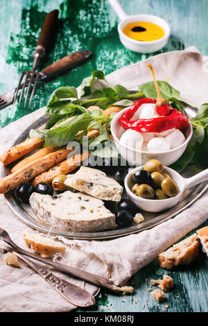 Gemischte antipasti Blau Käse, Oliven und Mozzarella serviert auf silbernem Tablett über grüne Holztisch mit Vintage Gabeln. Stockfoto