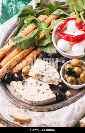 Gemischte antipasti Blau Käse, Oliven und Mozzarella serviert auf silbernem Tablett über grüne Holztisch. siehe Serie Stockfoto