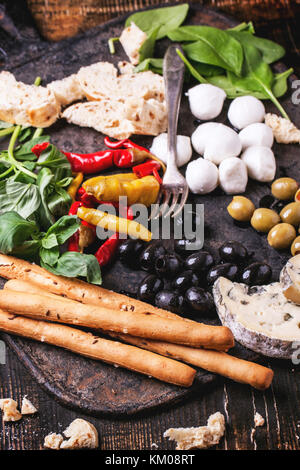 Gemischte antipasti Brot, Oliven und Mozzarella serviert auf gusseisernen Brett über Holztisch mit Vintage Gabel. Stockfoto