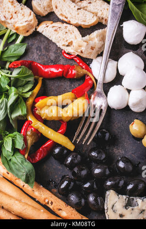 Gemischte Antipasti eingelegte Paprika, Oliven und Mozzarella serviert auf gusseisernen Brett über Holztisch mit Vintage Gabel. top View Stockfoto