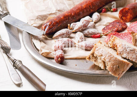 Satz von Wurstwaren Wurst mit frischem Brot und red hot chili peppers auf vintage Tablett serviert. Stockfoto