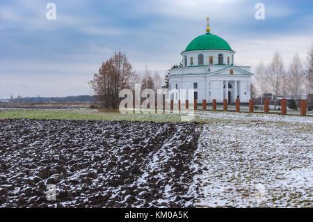 Landschaft mit landwirtschaftlichen Feldern in der Nähe einer alten Kirche von St. Nicholas (1797) in der städtischen Siedlung dikanka, Ukraine. Stockfoto