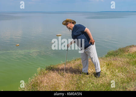 Einsame ältere Mann im blauen T-Shirt und leichte Hosen stehen auf erhöhten abrupte Riverside des dnipro River und nach unten schauen. Stockfoto