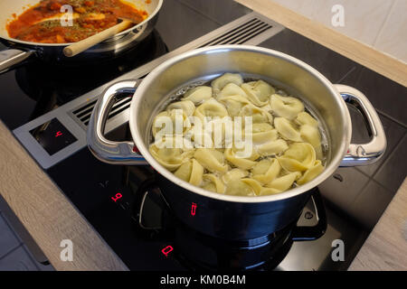 Topf mit Tortelling und Pan mit Tomatensauce auf einem Kochfeld Stockfoto