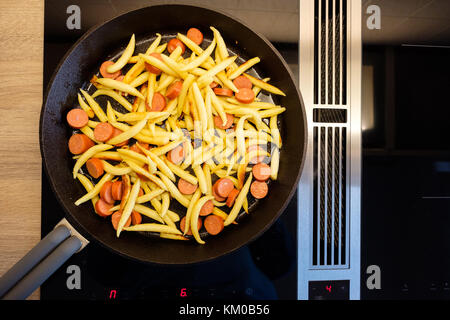 Ansicht von oben Finger geformte Kartoffelknödel in einer gusseisernen Pfanne auf einem Induktionsherd Stockfoto