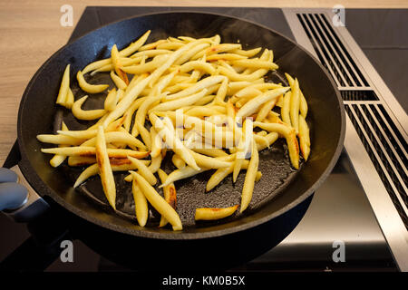 Kartoffelklöße braten in einer Pfanne Gusseisen auf einem Induktionsherd Stockfoto