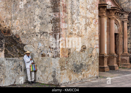 Ein mexikanischer Bauer ruht an einer Mauer am Templo del Sagrario in Patzcuaro, Michoacan, Mexiko. Stockfoto