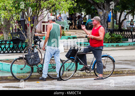 Zwei kubanische Männer in Moron gesehen, der Hauptstadt der Ciego de Avila Bezirk von Kuba, nach dem Tausch eines Ersatzteile Fahrrad Rad. Stockfoto