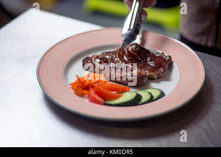 Chef beendete seine Platte und fast fertig am Tisch zu dienen Stockfoto