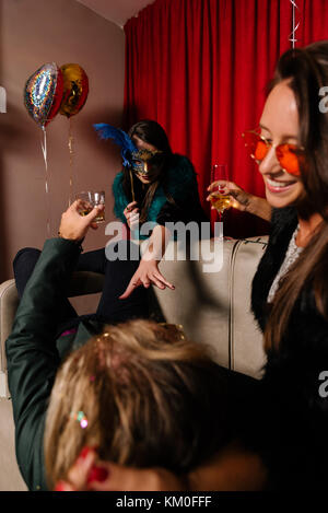 Maskierte Frau nähert sich jemand elses Mann auf einer Party Stockfoto
