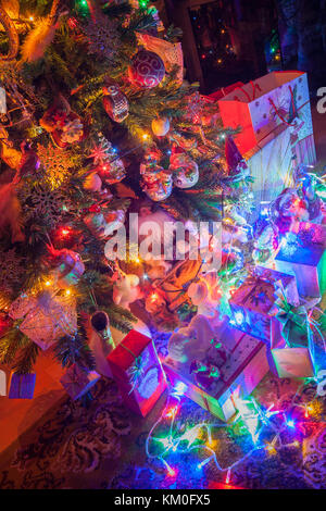 Geschenke und Weihnachtsschmuck neben einem leuchtenden Weihnachtsbaum Stockfoto