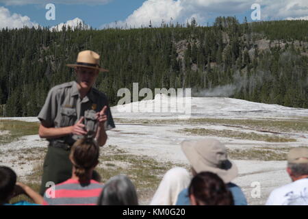 Ein Park Ranger in Uniform erklärt den Besuchern die Funktionsweise der berühmte Old Faithful Geyser. Yellowstone National Park, Wyoming. Stockfoto