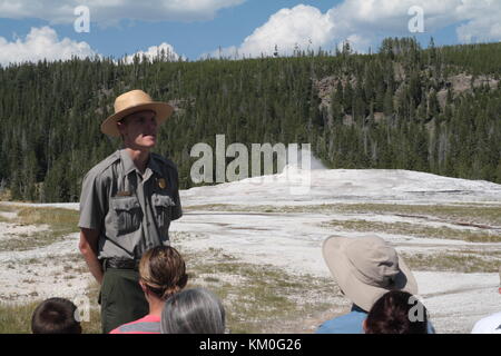 Ein Park Ranger in Uniform erklärt den Besuchern die Funktionsweise der berühmte Old Faithful Geyser. Yellowstone National Park, Wyoming. Stockfoto
