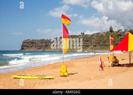 Rettungsschwimmer am Bungan Beach, Sydney, NSW, Australien mit Meereskopfland und Surfen, schwimmen zwischen den Flaggen Stockfoto