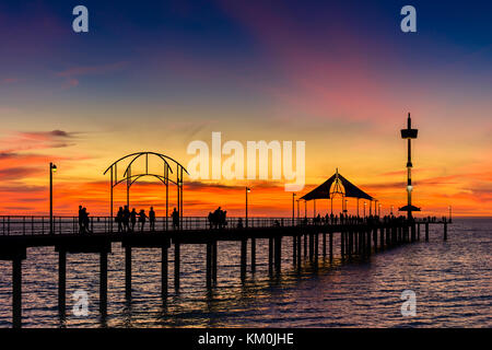 Menschen zu Fuß entlang der Brighton Pier bei Sonnenuntergang. South Australia Stockfoto