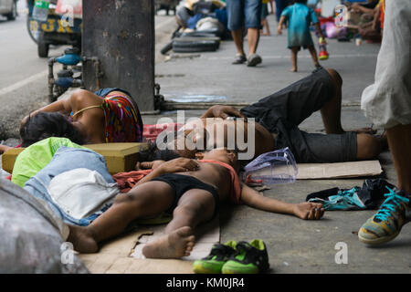 Ein Kind mit einem Mann & Frauen schlafen auf dem Bürgersteig während des Tages in Cebu City, Philippinen Stockfoto