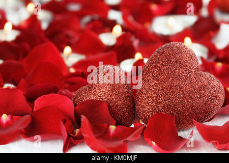 Valentinstag Herzen durch Rosenblätter und lite Kerzen vor einem weißen Hintergrund umgeben. Zimmer für Kopie Raum mit extrem geringer Tiefenschärfe. Stockfoto