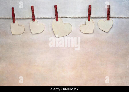Die Herzen der Holz- Liebe Valentinstag abgeschnitten zu Netzkabel durch rote Kleidung Pins über strukturierten Hintergrund mit Kopie Raum zur Verfügung. Stockfoto