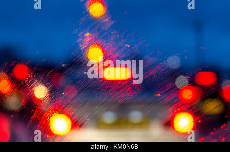 Straße und Auto Lichter durch Regentropfen auf dem Auto Windschutzscheibe bei Nacht, Liverpool, England, UK Stockfoto