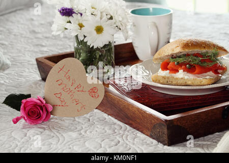 Handschriftliche Meldung des Kindes auf Herz Karte und Blumen mit Frühstück im Bett serviert. Extrem flache Tiefenschärfe mit selektiven Fokus auf Hören Stockfoto