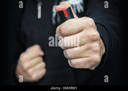 Ein Mann in schwarzen Uniformen und Handschuhe Tränengas oder Pfefferspray. Mittel der Selbstverteidigung. Gaskartusche, gas Aktivkohlefilter Stockfoto