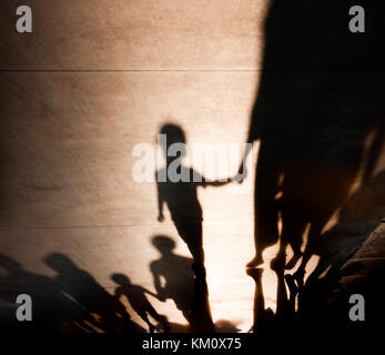 Heben zuversichtlich Kind: verschwommene Schatten Silhouetten von Familien mit Kindern wandern und, Hände auf misty Sommer Promenade, Kindheitserinnerungen Stockfoto