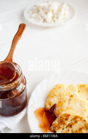 Quark Pfannkuchen, pflaumenmus in Glas und frischem Quark auf hölzernen Tisch. Selektive konzentrieren. Diagonale Komposition. Stockfoto