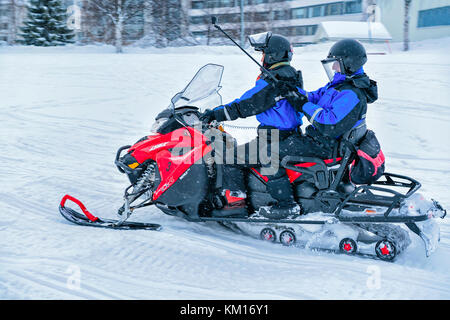 Rovaniemi, Finnland - 2. März 2017: Mann, ein Motorschlitten und Frau mit selfie Stick Fotos von sich selbst auf dem zugefrorenen See im Winter rovan Stockfoto
