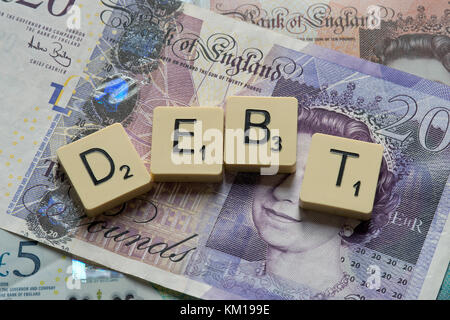 Scrabble Buchstaben Rechtschreibung Schulden mit neuen britischen Pfund (GBP) £ 20, £ 10, £ 5 Hinweise und neue britische Pfund Münzen. Stockfoto