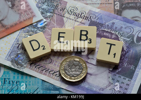 Scrabble Buchstaben Rechtschreibung Schulden mit neuen britischen Pfund (GBP) £ 20, £ 10, £ 5 Hinweise und neue britische Pfund Münzen. Stockfoto