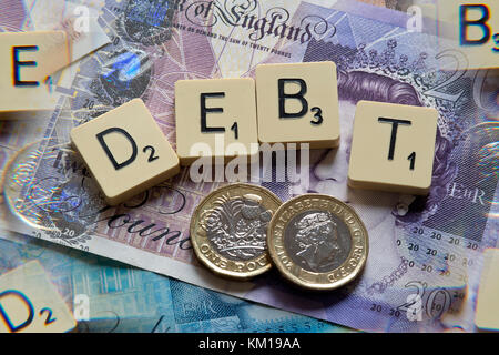 Scrabble Buchstaben Rechtschreibung Schulden mit neuen britischen Pfund (GBP) £ 20, £ 10, £ 5 Hinweise und neue britische Pfund Münzen. Stockfoto