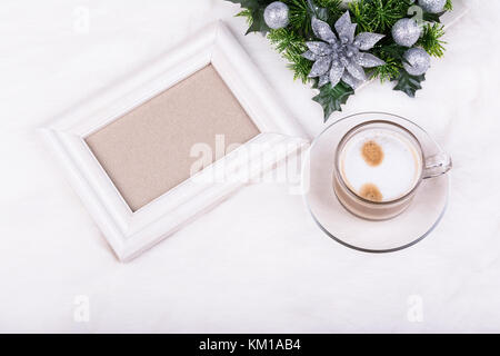 Weihnachtsdekoration, leeren Bilderrahmen und latte Kaffee auf weißem Hintergrund. weißen Rahmen Mock-up. Stockfoto
