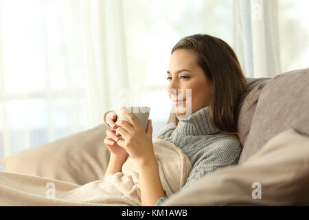 Entspannt Mieter ruht Holding eine Kaffeetasse sitzt auf einem Sofa im Wohnzimmer in einem Haus innen Stockfoto